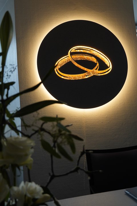 Beleuchtetes Kunstobjekt im Trauzimmer, das zwei goldene Ringe zeigt.