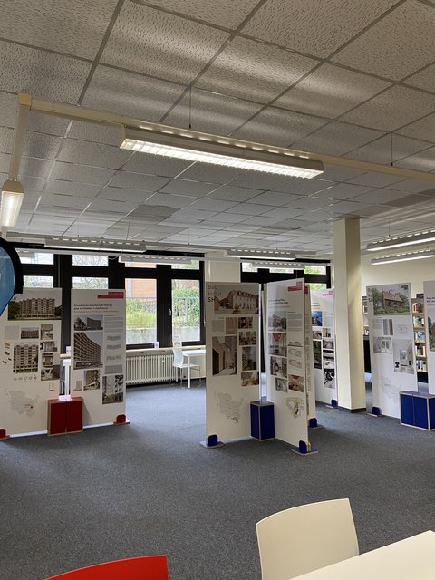 In der Stadtbücherei stehen große Pappaufsteller der Ausstellung Landespreis für Baukultur 25.–30.03.2026