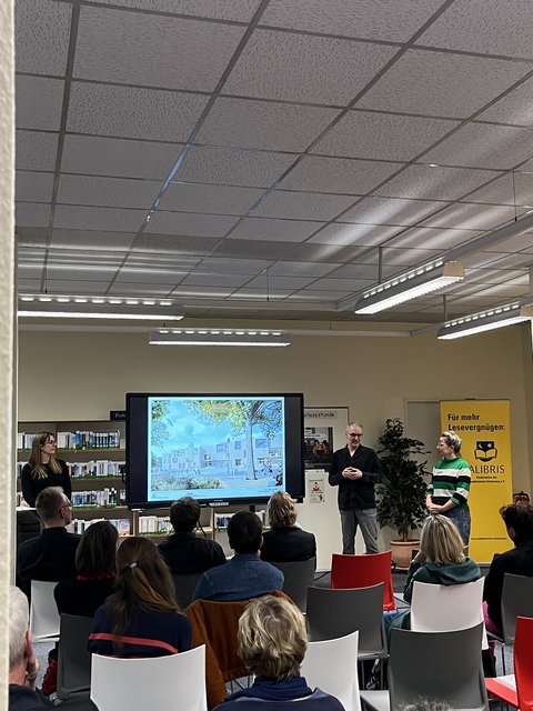 Präsentation Einblicke in Raumkonzept Parkhausquartier - Josie Schäfer (Stadtentwicklung), Frank Birwe (KBNK), und Jessica Christensen (Stadtbücherei) vor Zuschauer*innen in der Stadtbücherei
