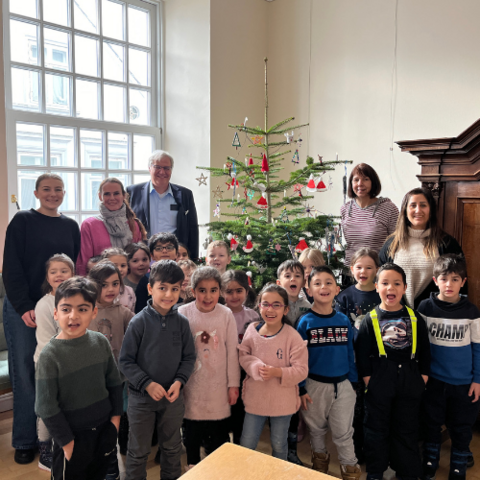 Gruppenfoto der Kinder mit Stephan Dose vor dem Weihnachtsbaum