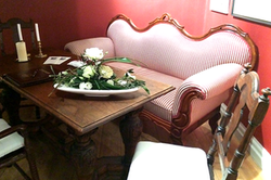ein rosanes Sofa stehend am Tisch und ein Blumengedeck auf dem Tisch