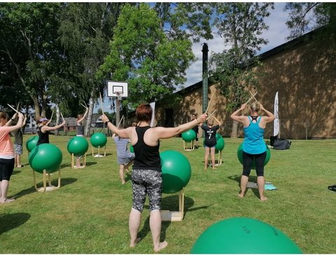 Teilnehmende des Kurses der Volkshochschule "Drums Alive® – Trommeln auf großen Bällen“ mit Bällen auf einer Wiese