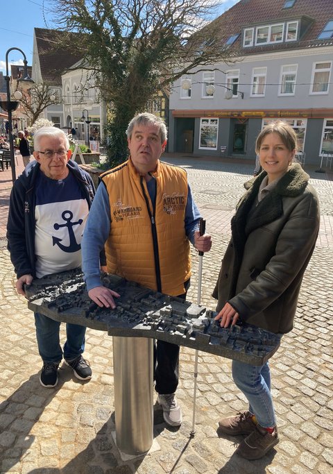 Horst Rieger (Behindertenbauftragter Stadt Schleswig) Carsten Lasarsch (Inklusives Schleswig) und Josephine Schäfer (Stadtplanung Stadt Schleswig) vor dem neuen bronzenen Stadtmodell am Kornmarkt