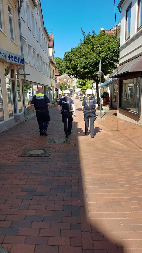 Gemeinsame Kontrolle von drei Personen der Polizei und Kommunaler Ordnungsdienst von hinten mit Blick in die Innenstadt, Stadtweg in Schleswig