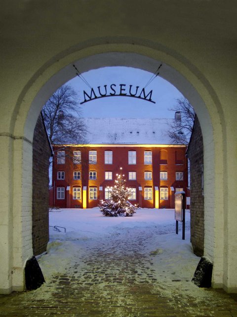 Verschneiter Hof vor dem Stadtmuseum mit einem beleuchteten Weihnachtsbaum