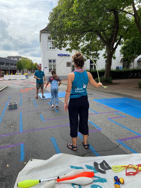 Drei Personen springen Springseil auf der bemalten Straße - Schwarzer Weg. 