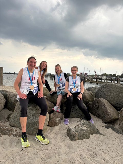 Läufer*innen Uwe Ströh, Anna, Skrobko, Christiane Carstensen und Kathrin Schäfer mit Medaillen "Lauf zwischen den Meeren" am Strand von Damp
