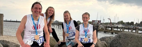 Läufer*innen Uwe Ströh, Anna, Skrobko, Christiane Carstensen und Kathrin Schäfer mit Medaillen "Lauf zwischen den Meeren" am Strand von Damp
