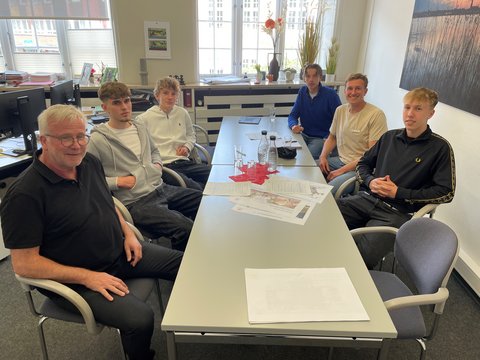 Tade Reinhardt, Theo Schenkel, Carlo Schieweck und Ben Richter im Gespräch mit Bauamtsleiter Bernward Völmicke und Nils Clasen (Bürger*innenbeteiligung) am Schreibtisch im Bauamt