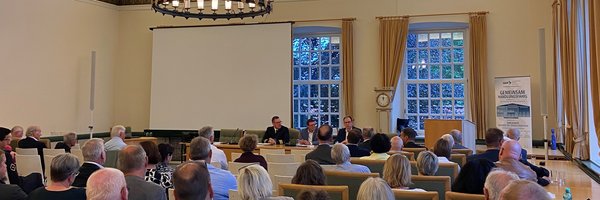 Flottillenarzt Oesemann, Kapitän zur See a. D. Dirk Peddinghaus und Staatssekretär Dr. Olaf Tauras im voll besetztem Ständesaal