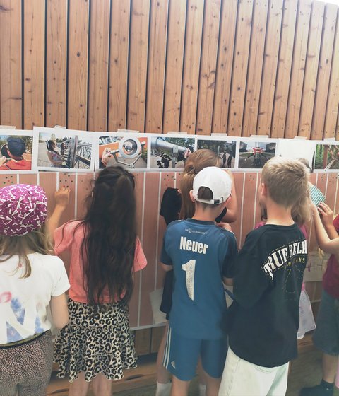Kinder von hinten an einer Bilderwand