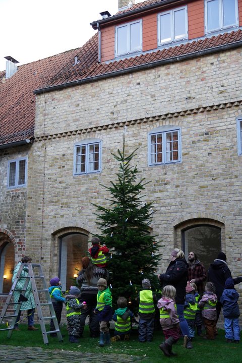 KInder und Erzieher*innen schmücken den Weihnachtsbaum im Innenhof des Rathauses