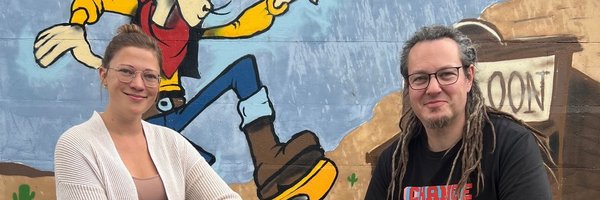 Streetworker*innen Schleswig - Marie-Louise Finger und Tobias H. Müller vor einer Sprayerwand, auf der Lucky Luke zu sehen ist.