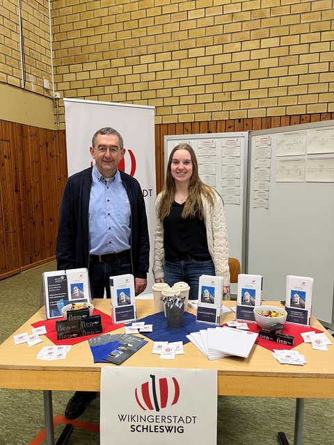 Norbert Krüger und Julia Sell aus dem Fachdienst Personal der Stadt Schleswig hinter einem Messestand der Stadt in der Dannewerkschule