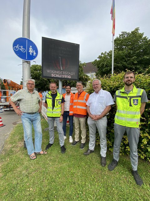 Dr. Johannes Thaysen (Vorsitzender BKU-Ausschuss), Torben Krüger (Fachdienstleiter Tiefbau), Yassin Benna und Michael Benna (beide Fa. Swarco), Bernward Völmicke (Fachbereichsleiter Bau) und Fabian Hundertmark (Fachdienst Tiefbau) vor der digitalen Anzeigetafel