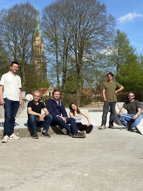 Mathias Heintz (AktivRegion Schlei-Ostsee) , Jens Bagehorn-Delor, (Stadtentwicklung/Öffentliches Grün), Linus Wirwoll und Jette Springer (Jungendkonferenz), Christian Sievers (Jugendzentrum), Jan Marthiensen (Karma Parks) und Dirk Lücke (Büro Studio L2) an der im Bau befindlichen Skateanlage. Im Hintergrund Bäume und der Dom