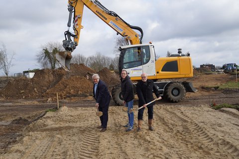 Erster Spatenstich Schützenredder: Stephan Dose (Stadt Schleswig), Tim Vorpahl u. Andreas Krey (Altstädter St. Knudsgilde) auf der Baustelle. Im Hintergrund ist ein Bagger zu sehen.