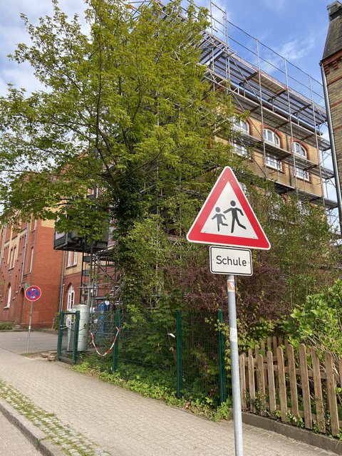 Gerüst am Gebäude der Wilhelminenschule mit einem Verkehrsschild Schule