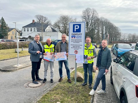 Zeitweise Freigabe der VR-Parkplätze: H. Schütze (Stadtmarketing), D. Jürgensen (FD Tiefbau), M. Möller (Vorstand VR-Bank Nord), T. Krüger (FD-Leiter Tiefbau) und R. Gottschalk (VR Bank Nord) vor einem Schild mit Öffnungszeiten