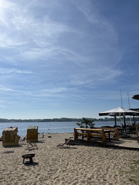 Bild zeigt das Luisenbad mit Blick auf Strandkörbe und die Schlei. Rechts ist Gastronomie zu sehen.