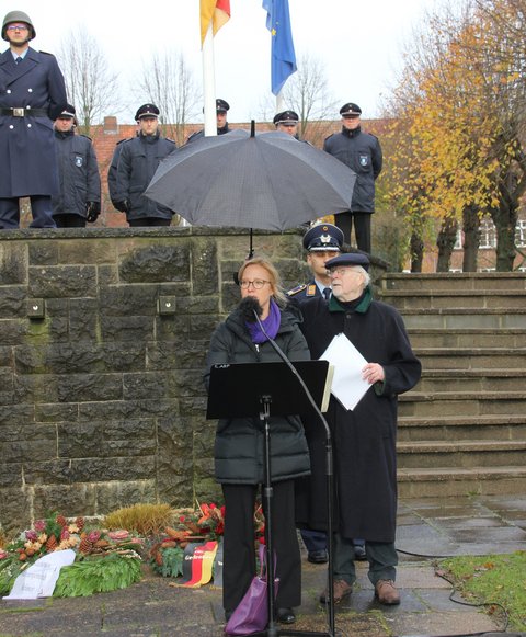 Bild zeigt Bischöfin Nora Steen und Hans-Peter Scheibel (AG Volkstrauertag) anlässlich des Volkstrauertages am 19.11.23 am städtischen Ehrenmal am Rosengarten in Schleswig