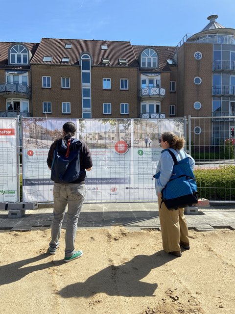 Besucherinnen vor den Visualisierungen entlang des Bauzauns