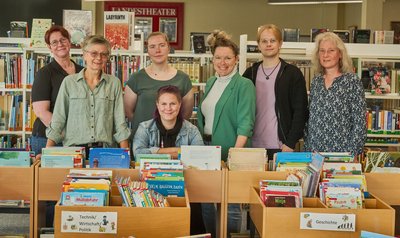 Zusehen die MitarbeiterInnen der Stadtbücherei Schleswig in mitten von Büchern