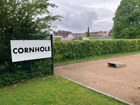 Schild Cornhole vor einer öffentlichen Grünanlage