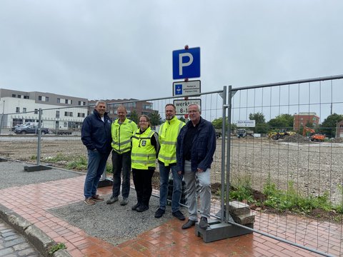 Helge Schütze (Stadtmarketing), Ove Jürgens (Firma Greve), Yvonne Lingner und Torben Krüger (FD Tiefbau) und Bernward Völmicke (Fachbereichsleiter Bau) an einem Parkschild und vor einem Bauzaun am ZOB