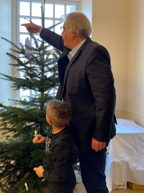 Stephan Dose und ein Kind eines städtischen Kindergartens hängen Weihnachtsbaumschmuck auf. 
