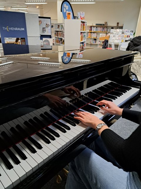 Hände spielen auf einem Musikinstrument, einem Flügel in der Stadtbüchereir Stadtbücherei lädt zum Musizieren ein