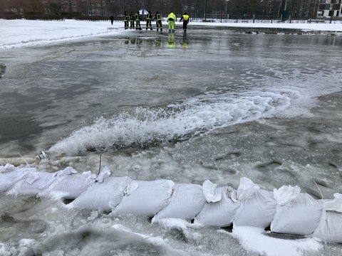 Eisfläche auf den Königswiesen, im Hintergrund Feuerwehrleute