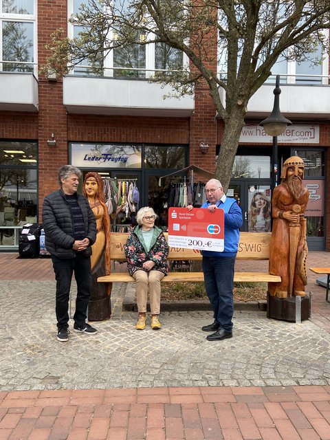 Ingo Harder, Renate Meier und Hans-Helmuth Jebe vor der Wikingerbank auf dem Capitolplatz