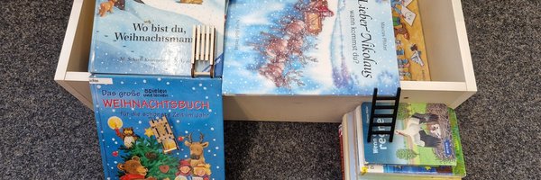 Weihnachtskinderbücher liegen in und vor eine Kiste ebenso wie ein Bücherstapel auf dem eine kleine Leiter gesetzt wurde