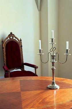 Kerzenständer auf Tisch, dahinter ein Stuhl