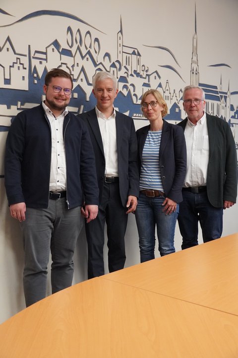 Jonas Kähler, Hayo Nadler, (Highstreet Group) Rowena Sandmeier und Bernward Völmicke (Fachbereich Bau) im Sitzungszimmer Schlein vor einer Schleswig-Grafik