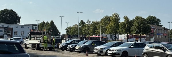 Parkende Autos und ein Straßensanierungsfahrzeug mit zwei Mitarbeitenden