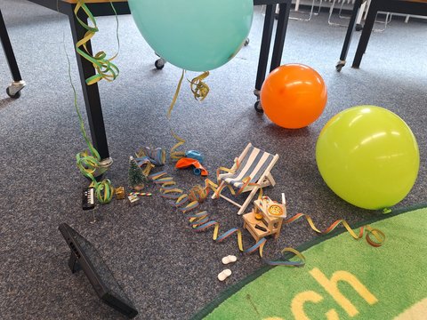 Miniaturliegestuhl, Luftballons, Luftschlangen auf dem Büchereiboden