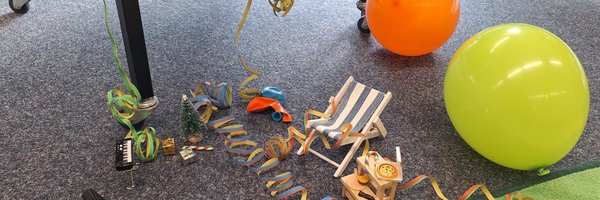 Miniaturliegestuhl, Luftballons, Luftschlangen auf dem Büchereiboden