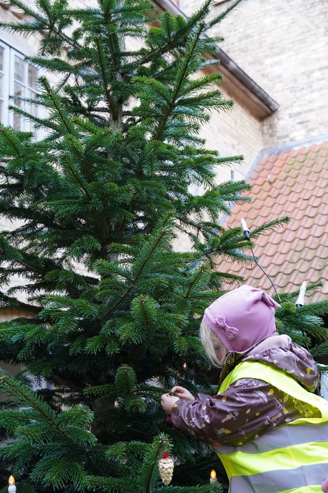 Mädchen schmückt den Weihnachtsbaum im Innenhof des Rathauses