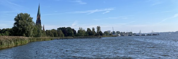 Blick über die Schlei auf den Steg am Hundestrand mit dem Schleswiger Dom im Hintergrund