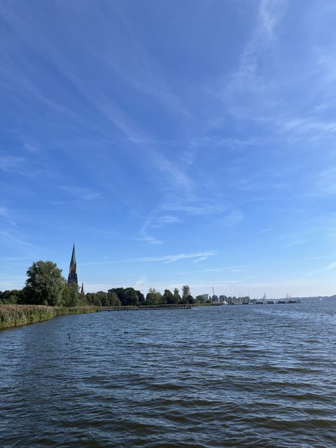 Blick über die Schlei auf den Steg am Hundestrand mit dem Schleswiger Dom im Hintergrund