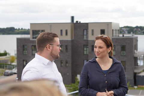 Innenministerin Magdalena Finke und Bürgermeister Jonas Kähler auf einer Dachterrasse im Baugebiet "Auf der Freiheit" mit Blick auf umliegende Gebäude und die Schlei