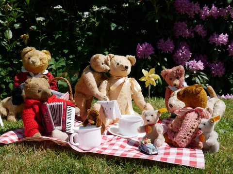 Teddybären auf eine Decke mit Miniaturgeschirr auf dem Rasen vor dem Stadtmuseum