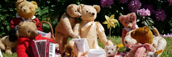 Teddybären auf eine Decke mit Miniaturgeschirr auf dem Rasen vor dem Stadtmuseum