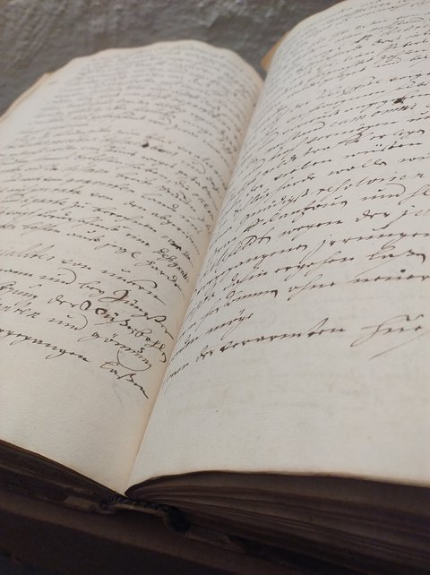 Bild zeigt ein aufgeschlagenes, handschriftlich beschriebenes Buch des Kreis- und Stadtarchivs