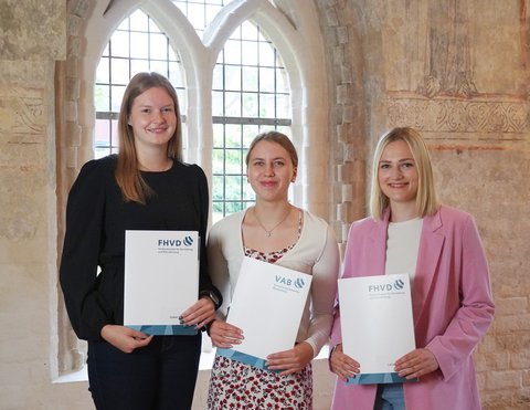 Isabel Hansen, Marisa Ruff und Lena Patzke haben ihre Abschlussprüfung bestanden und wurden im Gotischen Saal mit ihrer Urkunde abgebildet