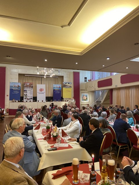 Blick auf Gäste am Tisch, die auf ein Rednerpult schauen