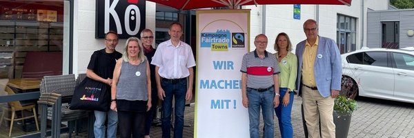 Auf dem Foto sind (von links nach rechts): Jörg Ziemert (Ziemert Folienbeschriftungen), Maren Korban und Inke Asmussen (Steuerungsgruppe Fairtrade-Stadt), Klaus Dieter Lemmermann (Bäckerei Schmidt), Matthias Hertel und Sina Clorius (Steuerungsgruppe Fairtrade-Stadt) sowie Bürgermeister Stephan Dose vor dem Café Kö.