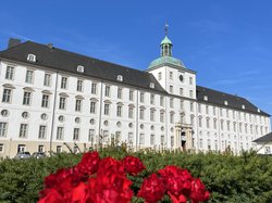 Foto zeigt das Schloss Gottorf mit roten Blumen im Vordergrund